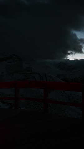 Young woman walking and pausing to look out over a vast mountain landscape.