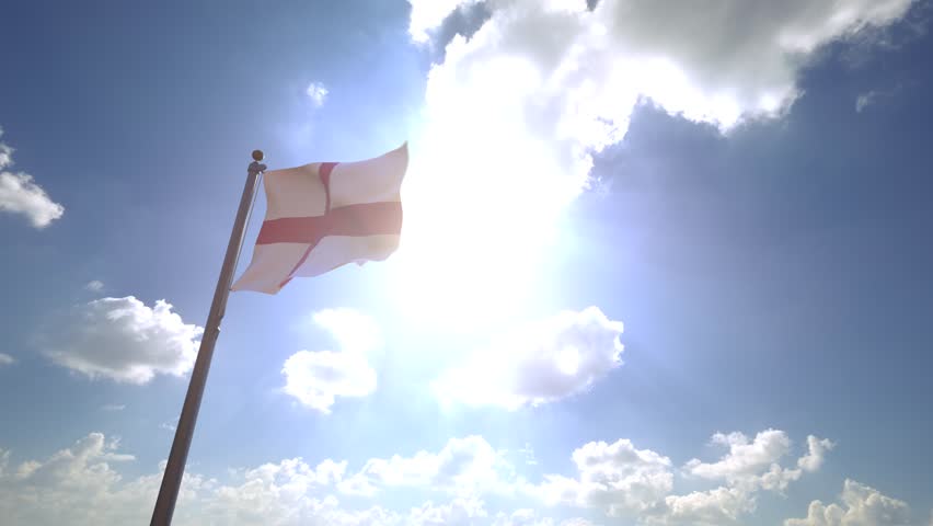 England Flag (UK) waving on a Flagpole from a Moving Angle in front of a blue sky with clouds