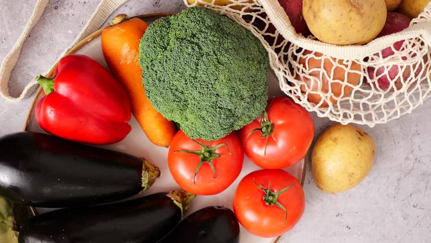 Variety of fresh vegetables including potatoes, tomatoes, eggplant, and broccoli displayed after grocery shopping
