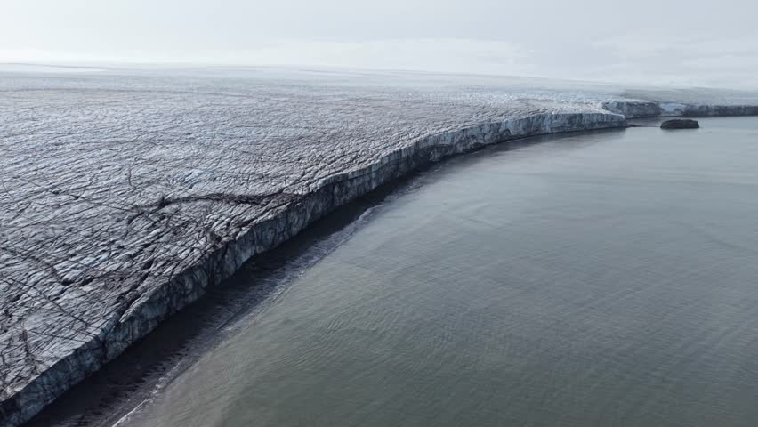 Cinematic flying in a rightward circular orbit to reveal the vast, crevassed surface of the Rotch Dome ice field and the dark volcanic shores of Elephant Point