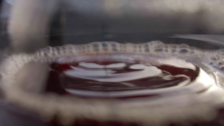 Macro close up of coffee drop hitting brewed coffee surface inside glass carafe