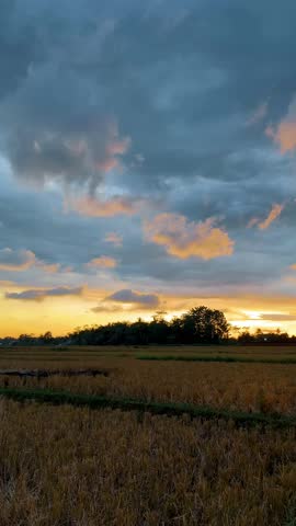 A sweeping photograph captures a vibrant sunset over a wide expanse of rural agricultural fields