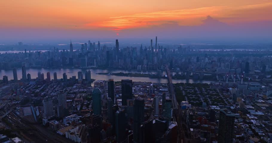 Hazy panorama of modern New York, USA. Drone footage high above the cityscape. Orange sky over the scenery.