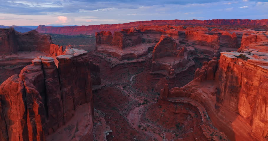 Moving among the tops of the striking red rocks lit by the setting sun. Extraterrestrial landscape of the Arches National Park, Utah, USA.