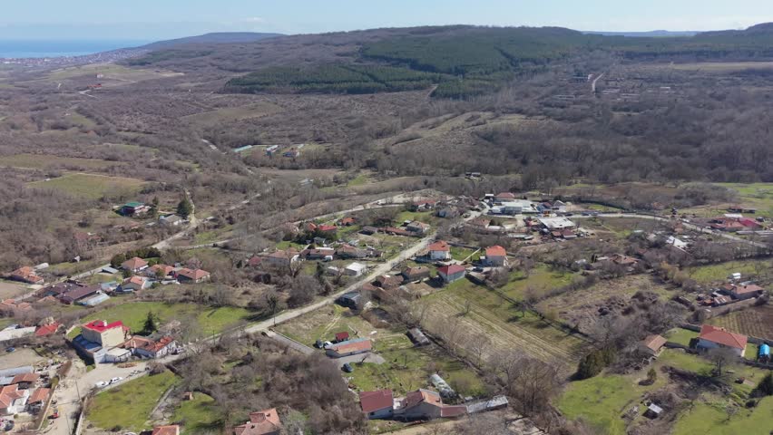 Aerial view of natural landscape with forest fields and distant hills under clear sky