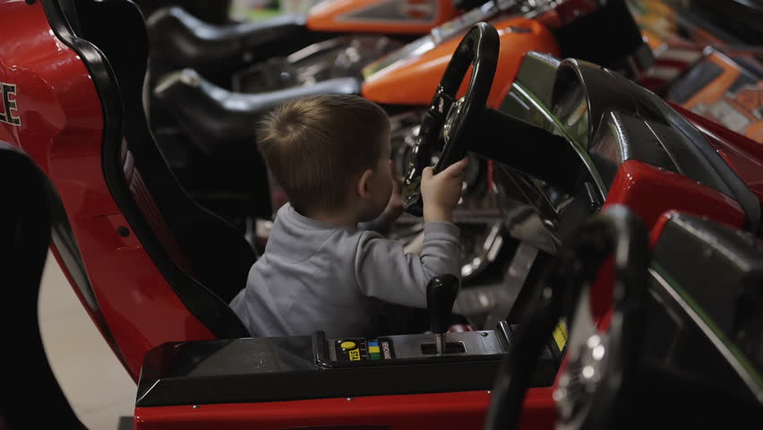 Little boy sitting in the toy car and holding a steering wheel