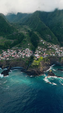 Drone aerial of Seixal village on Madeira island coastline, Atlantic Ocean and green mountains