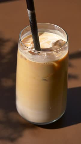 Creamy iced coffee with a thick straw shared on a sunny day