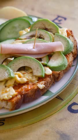 Enjoy a hearty open-faced sandwich with egg, avocado, and ham on bread