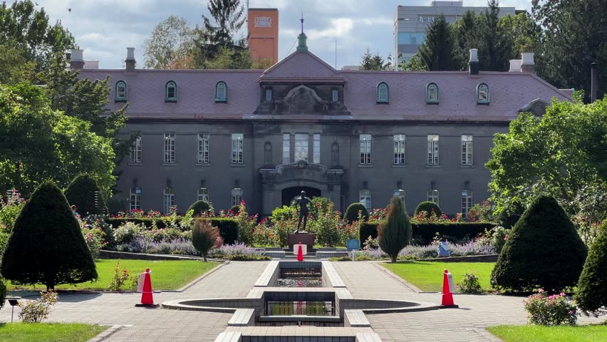 Scenery of Sapporo Shiryokan, a historical building at Odori Park in Hokkaido, Japan. A retro western-style building with a beautiful garden on a bright sunny day.