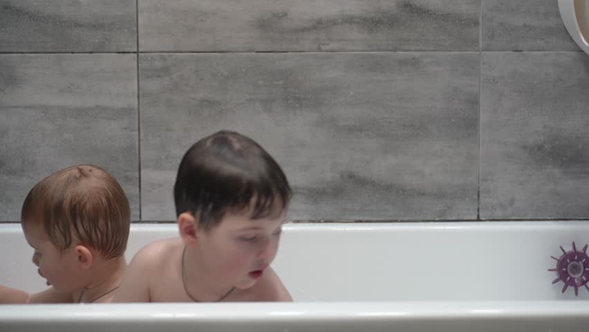 Two little boys having fun while taking bath in bathtub. Little children playing in the bath during the bathing.