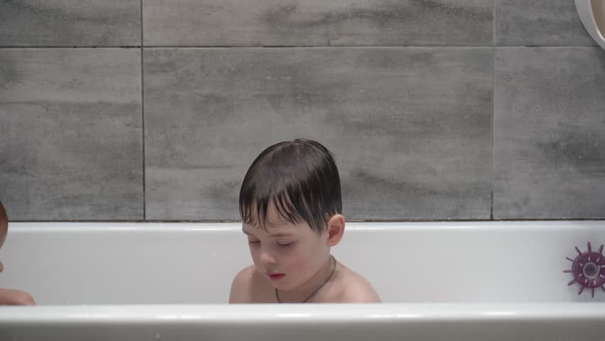 Two little boys having fun while taking bath in bathtub. Little children playing in the bath during the bathing.