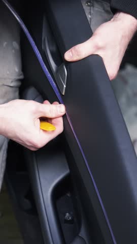 male craftsman inserts a backlight into a car door, installing a car backlight, professional service, tuning