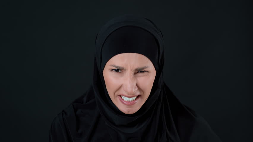 Woman With Light Skin Wearing a Black Hijab Shows an Emotional Expression Against a Dark Background