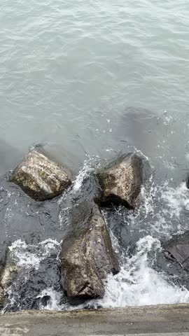 Strong Waves Crashing on Rocky Shore of Lake Michigan in Sheboygan: Powerful waves hitting the rocky shoreline of Lake Michigan in Sheboygan. Dynamic water movement creating splashes and natural textures along the coast.