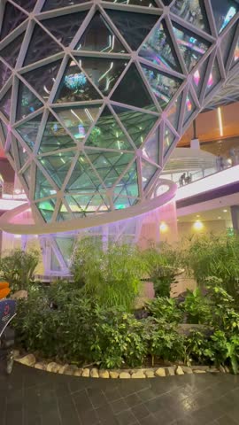 Top view of indoor waterfall and surrounding architectural landscape inside Hamad International Airport in Doha Qatar showing modern terminal design and interior structure.
