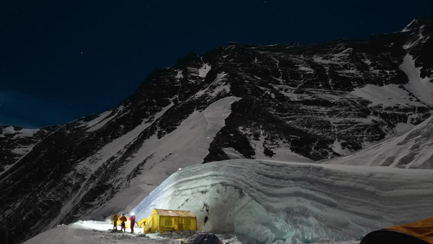 Expeditions climbing the Khumbu Icefall on Mount Everest with headlamps under a starry night sky