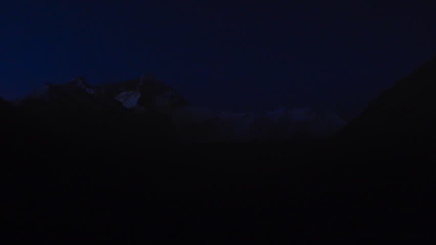 Group of climbers with headlamps walking in a row in the dark on Mount Everest
