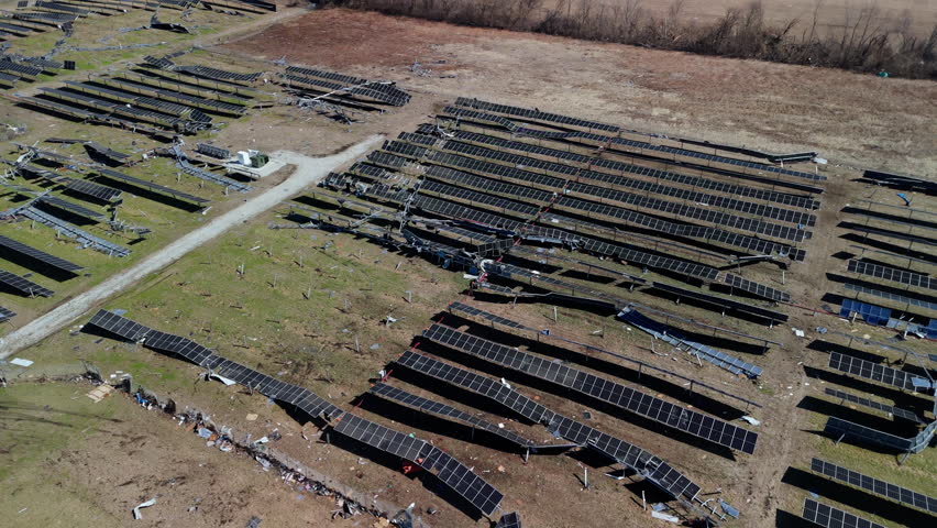 Wide aerial shoot of a solar energy field destroyed by a tornado with broken panels scattered across the ground.