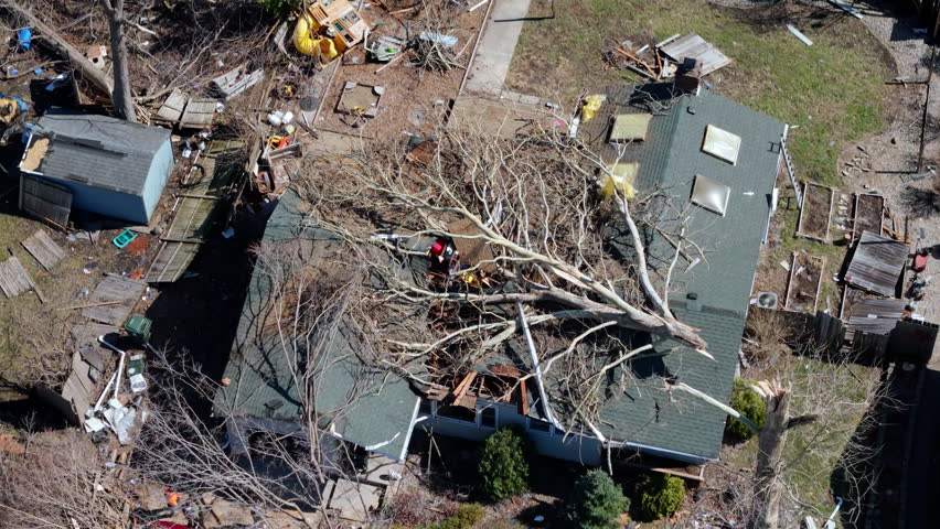 Drone view of tornado destruction in a suburban area with damaged houses. trees on roof and widespread debris.