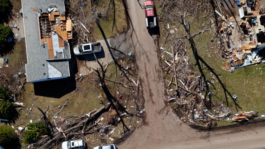 Drone top down shoot of residential neighborhood destruction after a tornado with damaged houses and scattered debris.