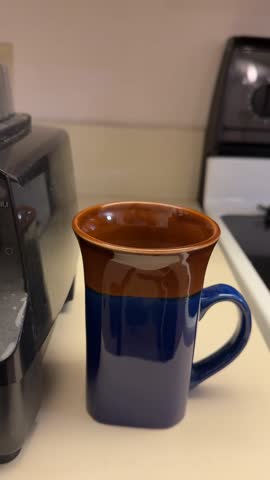 Close-up of Orange and Banana Juice Smoothie Being Poured into Ceramic Mug on Kitchen Counter, Smooth Liquid Motion with Soft Indoor Lighting, everyday home lifestyle healthy scene.
