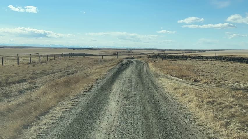 Driver POV on rural dirt road through open countryside landscape with natural terrain and wide horizon