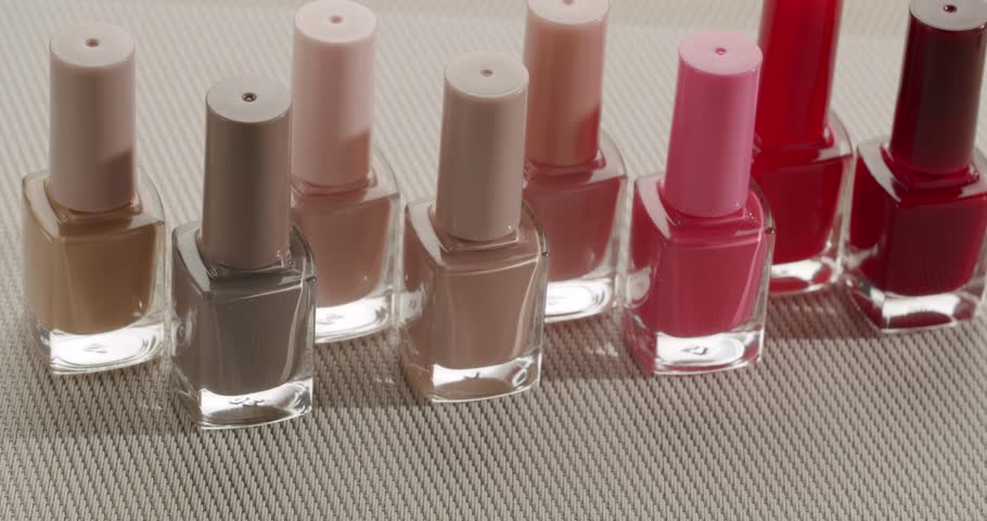 Colorful selection of nail polish bottles arranged in rows on a textured surface, showcasing a vibrant palette of shades for a perfect manicure and professional nail art in a beauty salon