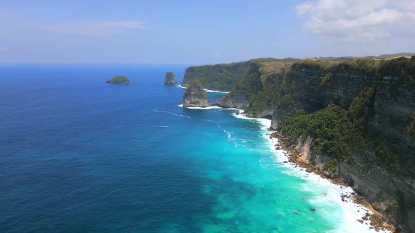 Aerial drone view of tropical coastline with cliffs and turquoise ocean in Nusa Penida Island, Bali, Indonesia. Scenic landscape and popular travel destination in Southeast Asia.