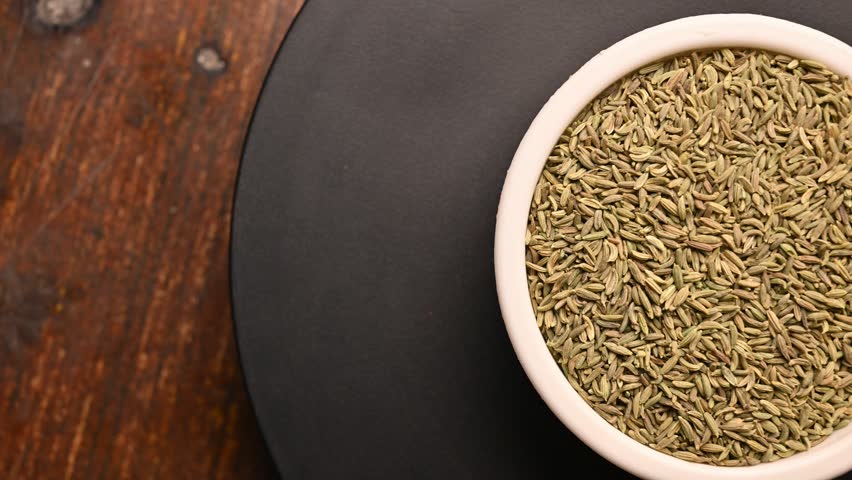 Top View of Fennel Seeds (Somp) in White Bowl on Black Background – Rotating Footage