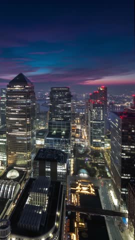 Night to day sunrise time lapse view of the skyline at the financial district Canary Wharf in London, England, with haze and colorful cloudscape