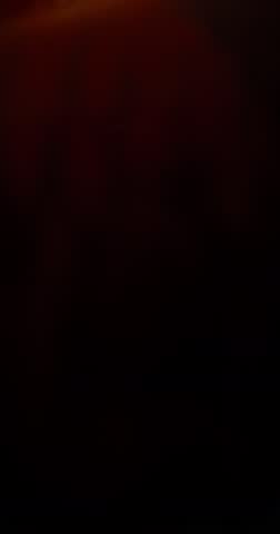 Extreme super slow motion of milk swirling and mixing into coffee, creating smooth creamy clouds and fluid abstract shapes in a dark liquid background. Speed ramp effect. Vertical aspect ratio.