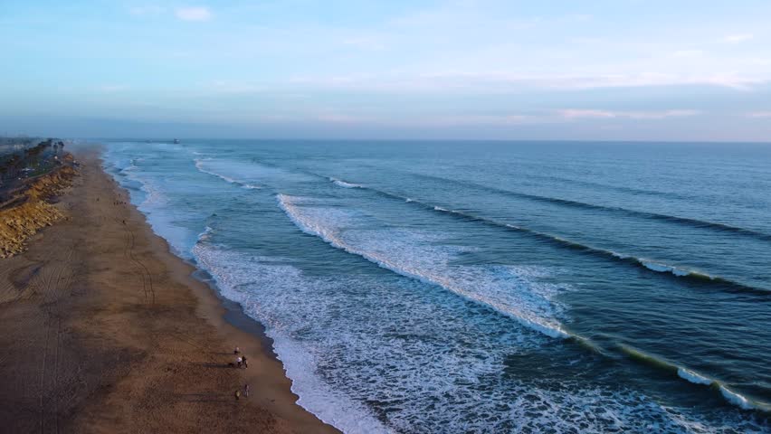 Warm sunset at coastal beach, golden hour light on calm Ocean waves. Scenic landscape of Huntington Beach, Orange County, California. Peaceful serene nature with calming view of horizon.