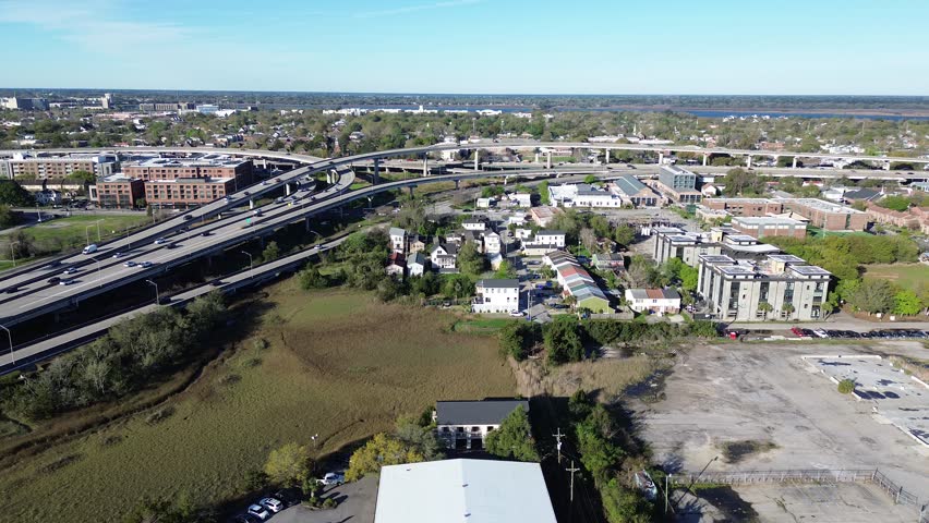 East Bay and Meeting St converge beneath elevated ramps linking Upper Peninsula to downtown Charleston. Varied rooflines, pavement tones, scattered foliage across mixed-use blocks, South Carolina. USA