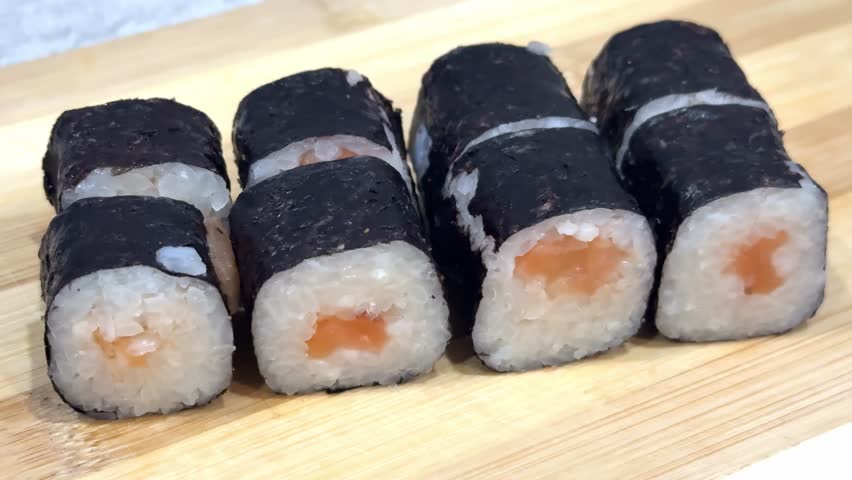 Delicious traditional japanese sushi maki rolls with salmon and rice wrapped in nori seaweed. Healthy asian food on a wooden platter