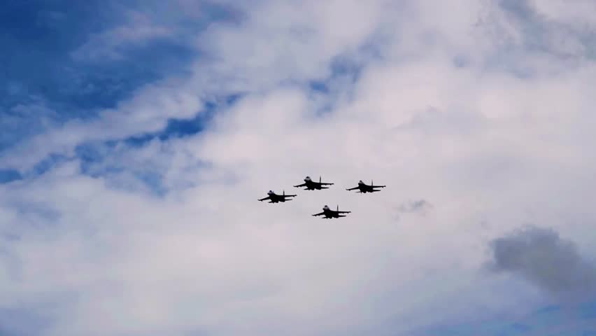 Dynamic display of aerial supremacy as four advanced fighter jets perform synchronized maneuvers with smoke trails against a clear blue sky demonstrating precision formation flying and tactical air power