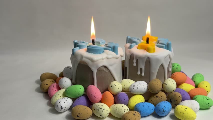 Decorative Easter cupcake candles with white frosting and pastel wax figurines among colorful Easter eggs