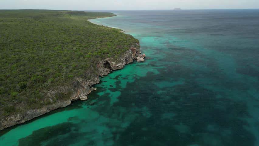 Wide drone shot showing cliff formations and surrounding tropical environment on Beata Island. Ideal for tourism campaigns.