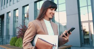 Business woman employee chatting online, texting using a smartphone walking on the street near an office building corporate office typing text messages on mobile phone checking emails successful - Powered by Shutterstock - Get 15% off with code: PIKWIZARD15