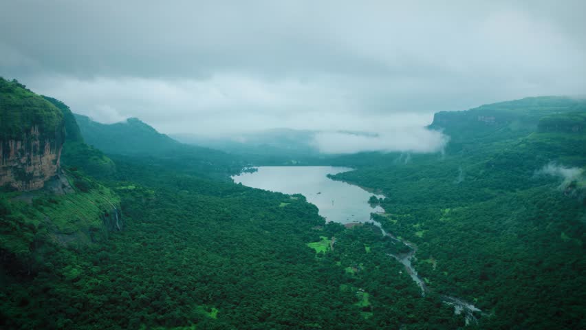 Scenic view of the lush green Western Ghats covered by clouds. 4K Aerial view of Bhira dam and lush green Sahyadri hills as seen from Savalya Ghat in Maharashtra, India. Rainy weather during monsoon in Sahyadri hills. Nature landscape and travel background.