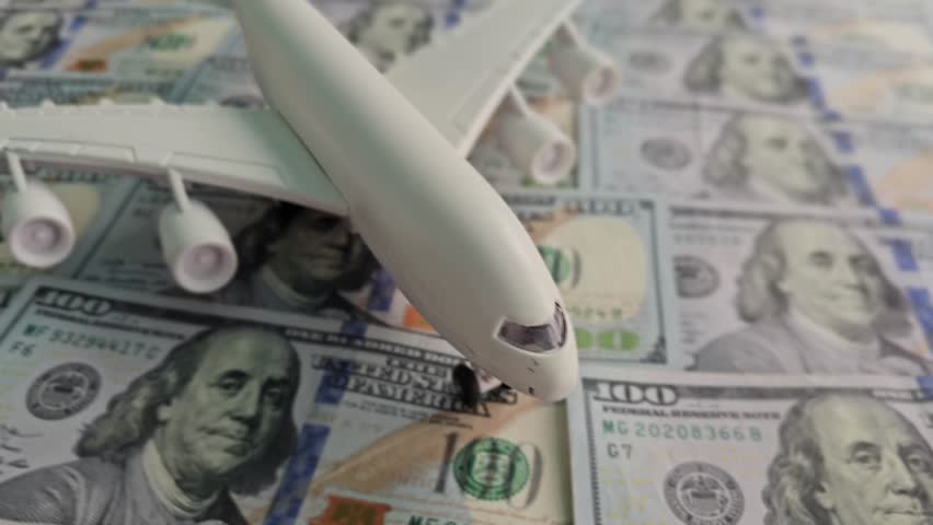 Model airplane sits on pile of money in a creative display at a studio setting