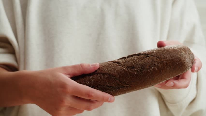 Black rye bread close up, dark brown sliced loaf, borodinsky slavic food, square slices with coriander on white background