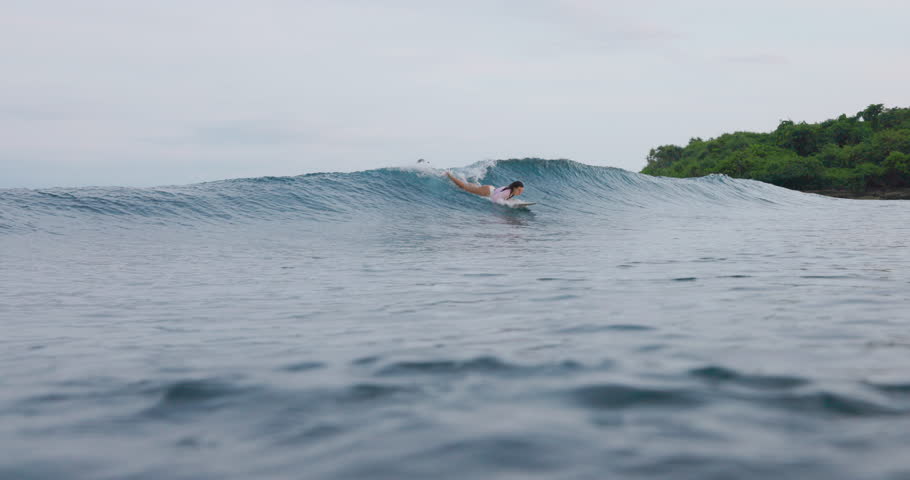 Surfer woman rides on ocean wave. Surfer girl during surfing.