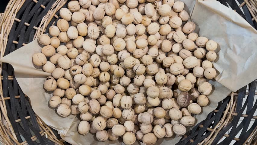 Walnuts in their shells in a woven basket, with natural organic nuts in the background, and a healthy eating concept.