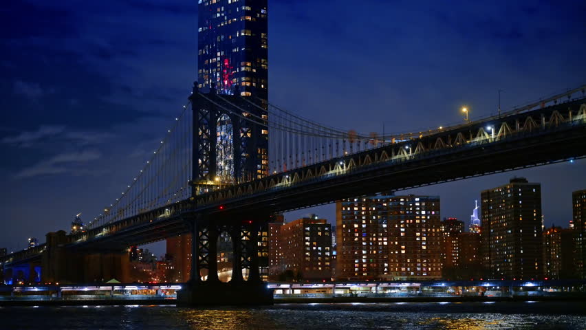 Night view of Manhattan Bridge and Brooklyn skyline. Long exposure of Manhattan Bridge over East River with illuminated city buildings and tower.