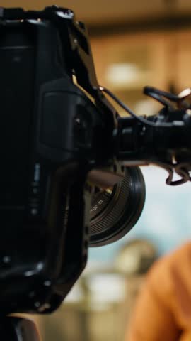 Behind the scenes of African American vlogger adjusting camera on tripod in home kitchen studio. Content creator checks lighting settings and steady framing during preparations, ready for filming.