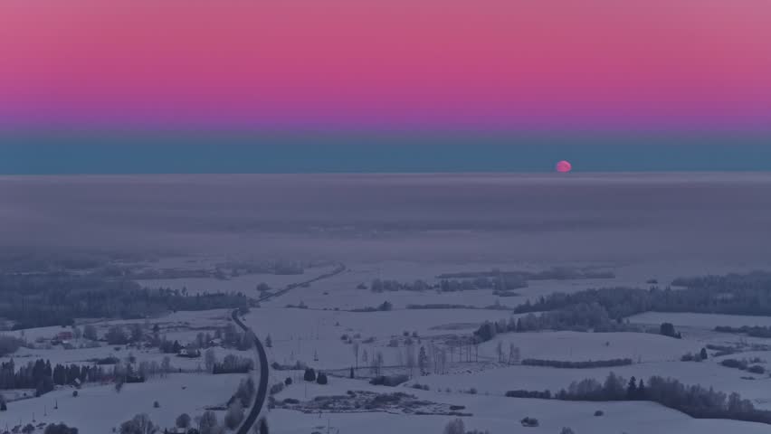 Pink sunset over a white snowy tundra landscape. Aerial