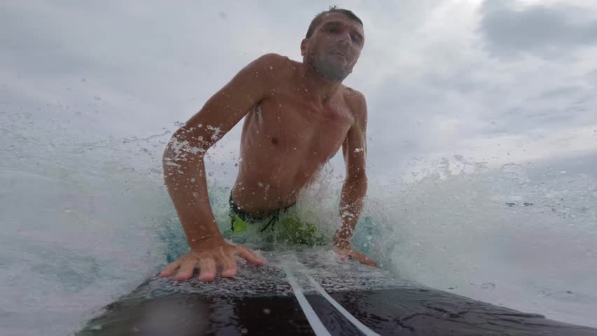 Man surfer on black surfboard rides a wave in ocean.  