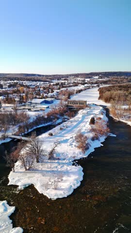 Hydroelectric Plant Waterway on the Trent River in Frankford Ontario Canada During Winter Snow. Vertical Aerial Panning Shot.