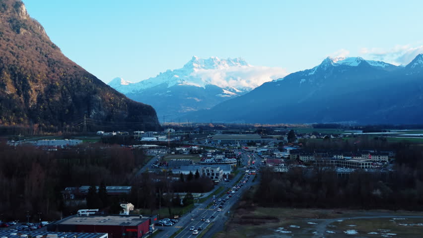 Aerial: Dents du Midi from Villeneuve industrial zone at sunset in Canton of Vaud, Switzerland, push in drone shot